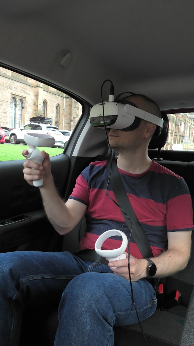 A study participant wears a VR headset while travelling in a car