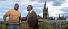 Two men stand on an outdoor platform overlooking Uniersity of Glasgow's main campus.