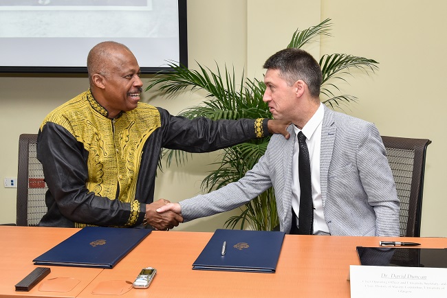 Professor Sir Hilary Beckles (seated left), Vice-Chancellor of The University of the West Indies (The UWI) and Dr. David Duncan, Chief Operating Officer & University Secretary, University of Glasgow, shake hands following the signing of the Memorandum of Understanding at The UWI Regional Headquarters, Kingston, Jamaica on July 31, 2019, to partner in a reparations strategy