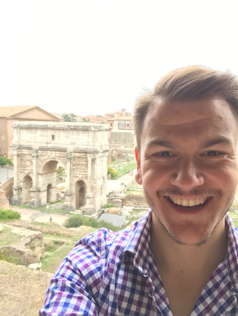 Alex stands in the Roman Forum, before the arch of Septimius Severus.