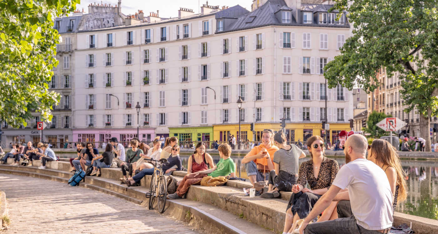 People sitting talking and socialising on the banks of the Canal Saint Martin [Photo: Shutterstock]