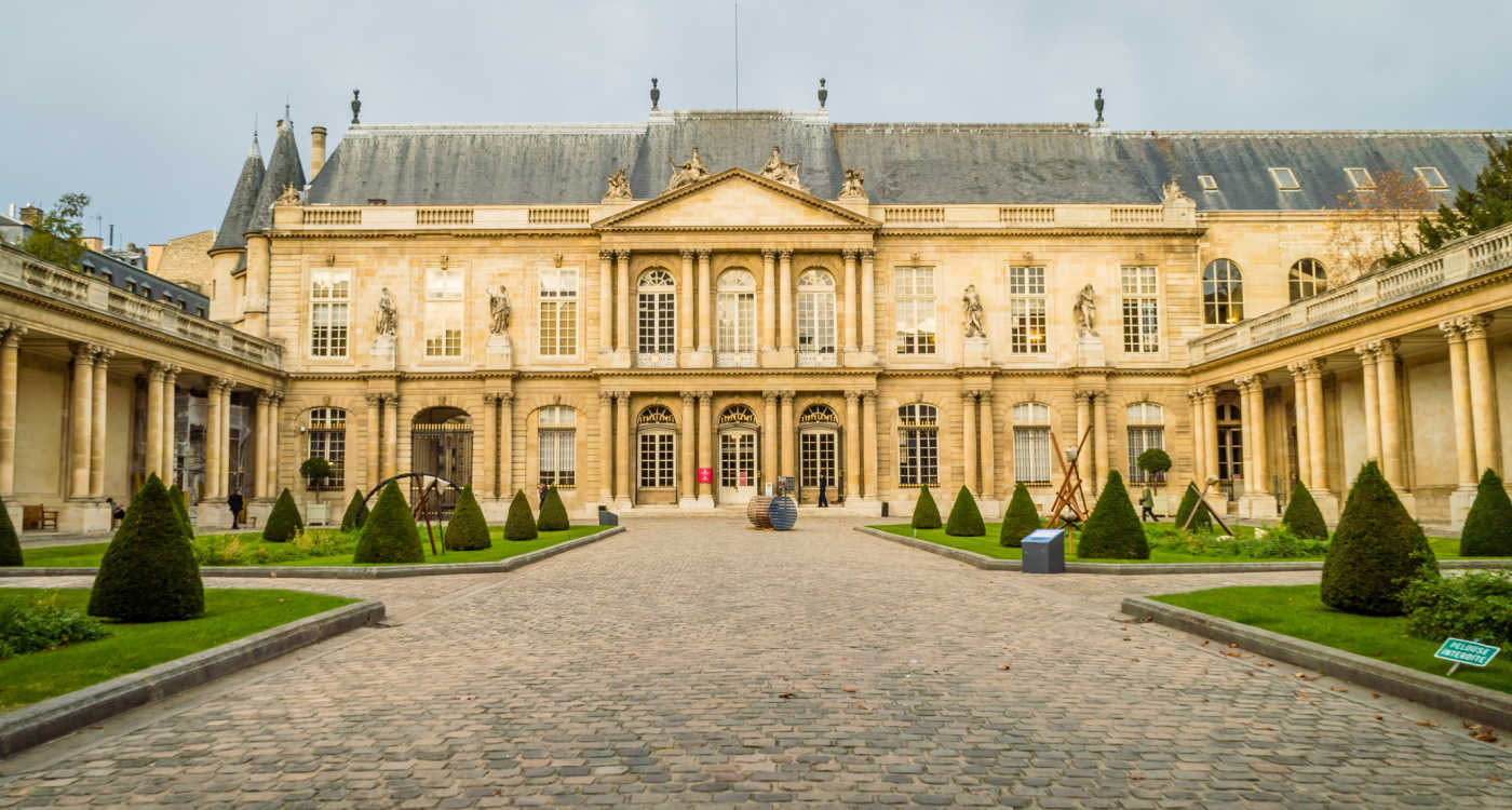 Outside view of Carnavalet museum in Paris - a yellow sandstone grand buiilding with manicured gardens in front [Photo: Shutterstock]