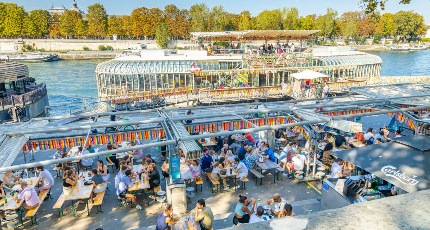 People sitting at the terrace of Peniche Rosa Bonheur - a boat-like pub - on the quays of the Seine river on a sunny day [Photo: Shutterstock]