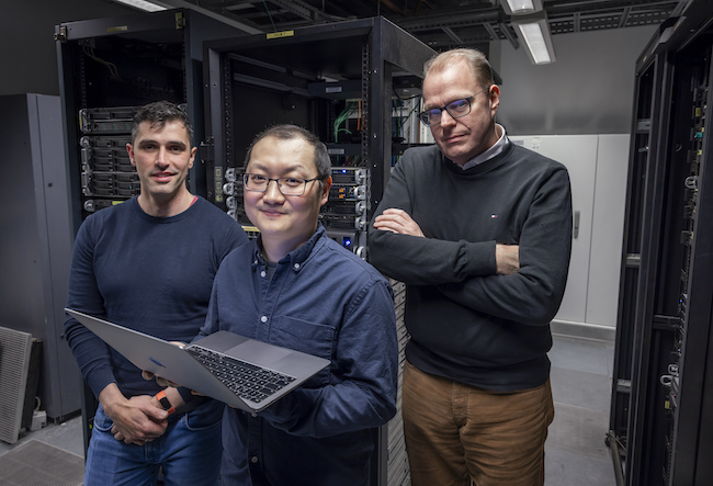Dr Adalberto Claudio Quiros,  Dr Ke Yuan and Professor John Le Quesne stand in a data centre at the University of Glasgow’s School of Computing Science.