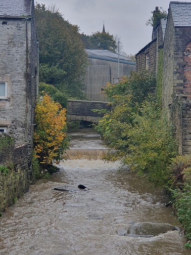 An urban river with weir and penned in by walls