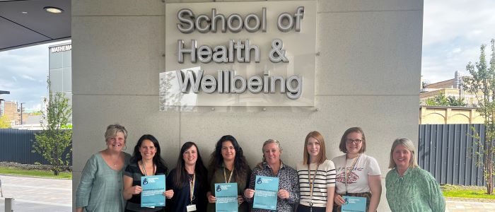 Photo of SHW staff standing outside the Clarice Pears building receiving Breastfeeding Friendly Scheme certificates in September 2023
