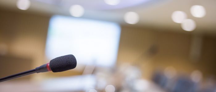 Photo of a microphone  at the front of a conference hall with blurred background