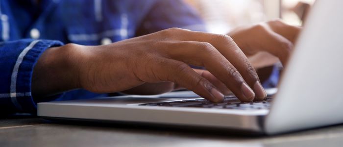 Photo of person in blue shirt using laptop