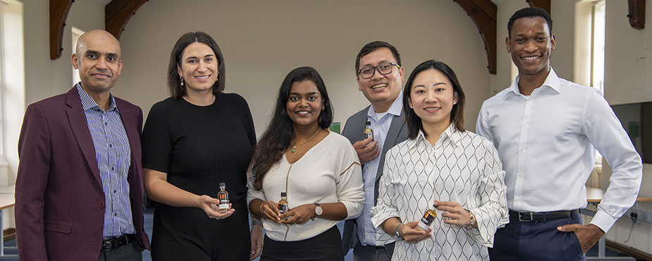 A group photo of business students holding miniature bottles