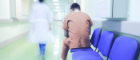 A prisoner sits in a hospital corridor