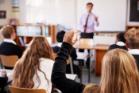 School pupils in classroom with male teacher at front