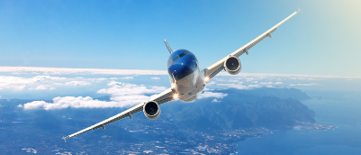 Airplane slying with blue sky and both land and sea in the distance