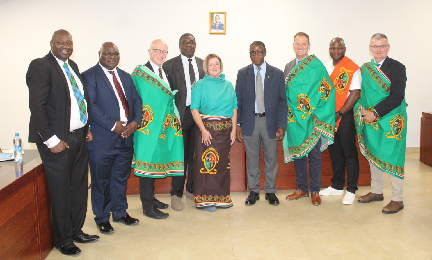 A University of Glasgow and Scottish Government Delegation stood in a line wearing traditional Zambian attire alongside University of Zambia