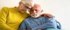 Elderly couple hold each other and look sad