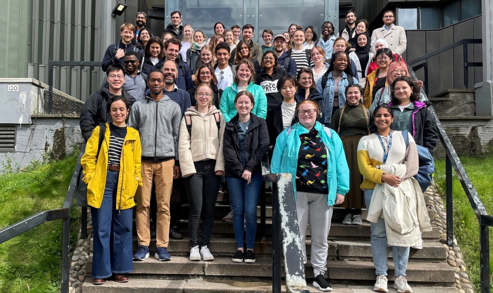 Participants from the summer school stood together as a group on the steps outside the UofG Boyd Orr Building