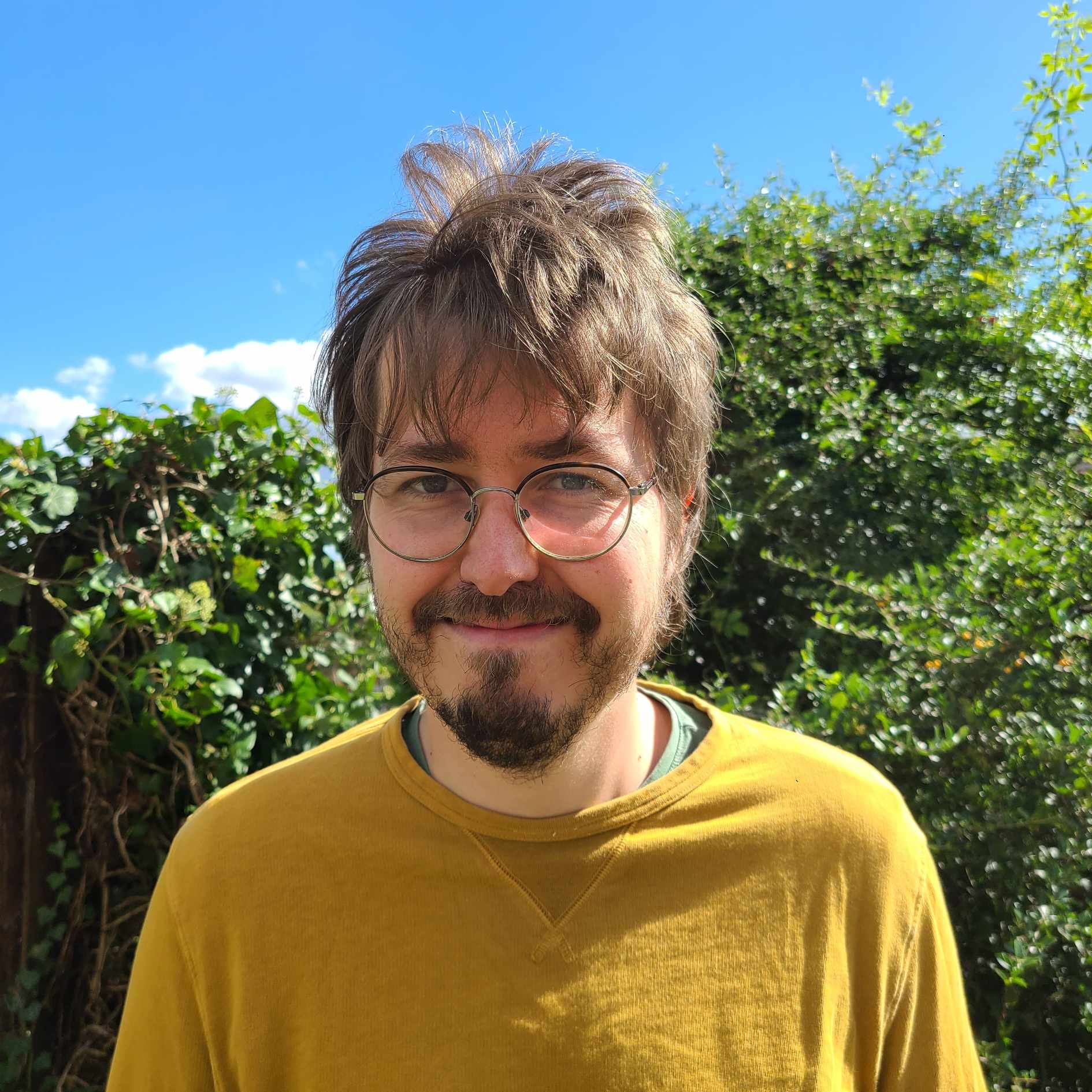 White man with beard and glasses and yellow jumper