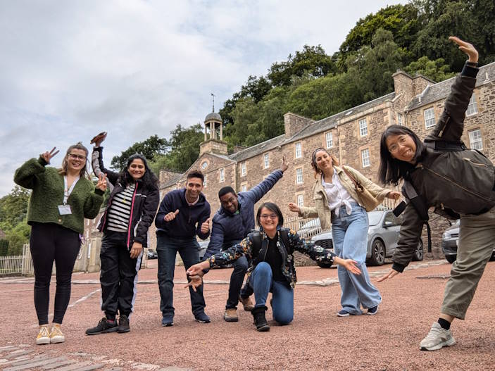 Group of seven people posing outside of the New Lanark Visitor Centre