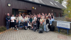 Level 3 Immunology students and Sii staff stood (and crouching) together in a group shout in front of the SCENE facility building