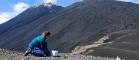 A researcher collecting samples next to a volcano