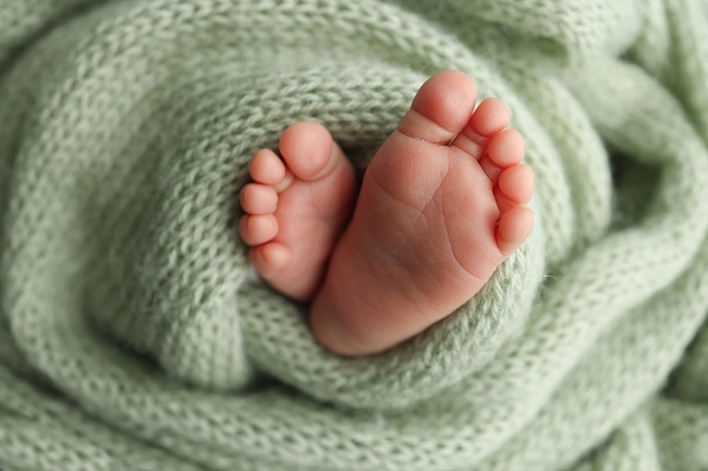 An image of a newborn baby's feet in a green blanket