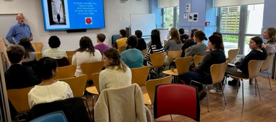 PGR Convener Dr Richard Burchmore presenting to a cohort of PGRs, sat in the SGDB common room