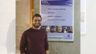 A photo of Dan in front of the Scottish Parliament Information Centre (SPICe) information board