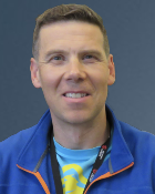 A head and shoulders shot of Professor Andy Roe against a blue background