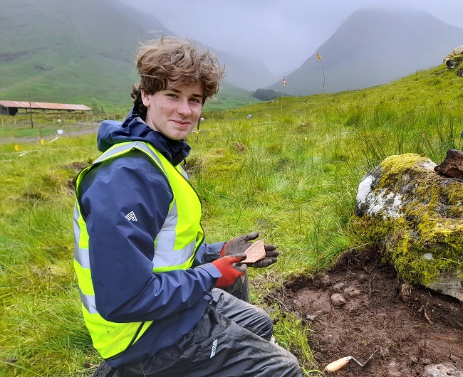 University of Glasgow undergraduate student Alexander McClure holds a 17th-century plate fragment he has just discovered. Photo: Derek Alexander.