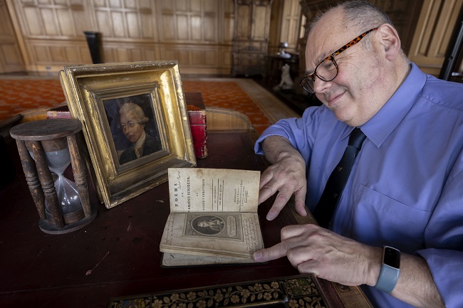 - Professor Gerard Carruthers at Barnbougle Castle sitting at the desk of the 5th Earl of Rosebery reading Robert Burns copy of a book of Robert Fergusson’s poetry with the newly discovered portrait of Robert Fergusson. Credit Martin Shields