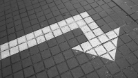 A photo of a downward pointing arrow painted on a pavement