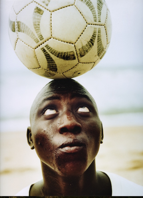 Close up photo of a man balancing a football on his head.