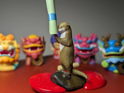 Small statue of an otter holding a scroll