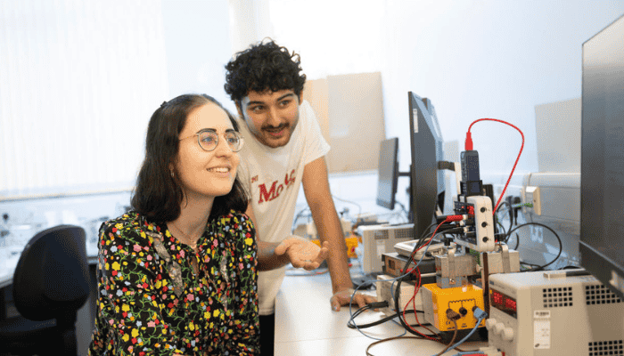 Two students working at a computer with engineering equipment