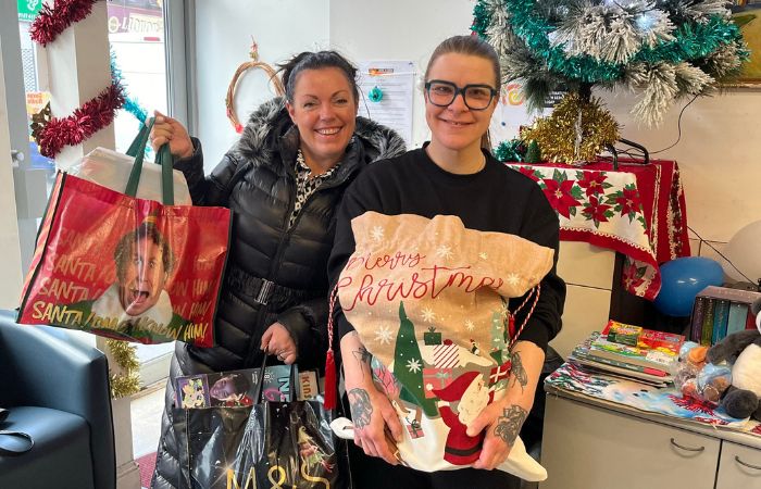 Two People Holding Bags Filled With Christmas Presents