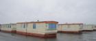 Photo of numerous stationary caravans outside on concrete ground against a grey sky