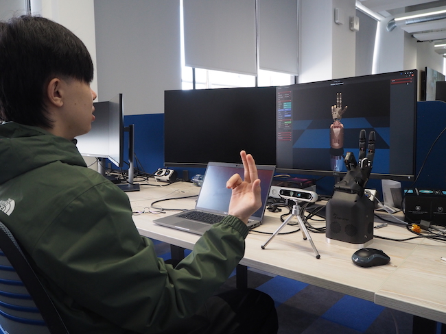 A student interacts with a robotic hand and associated digital twin