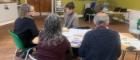 Four people are sitting round a table in a community centre.