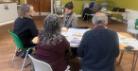 Four people are sitting round a table in a community centre.