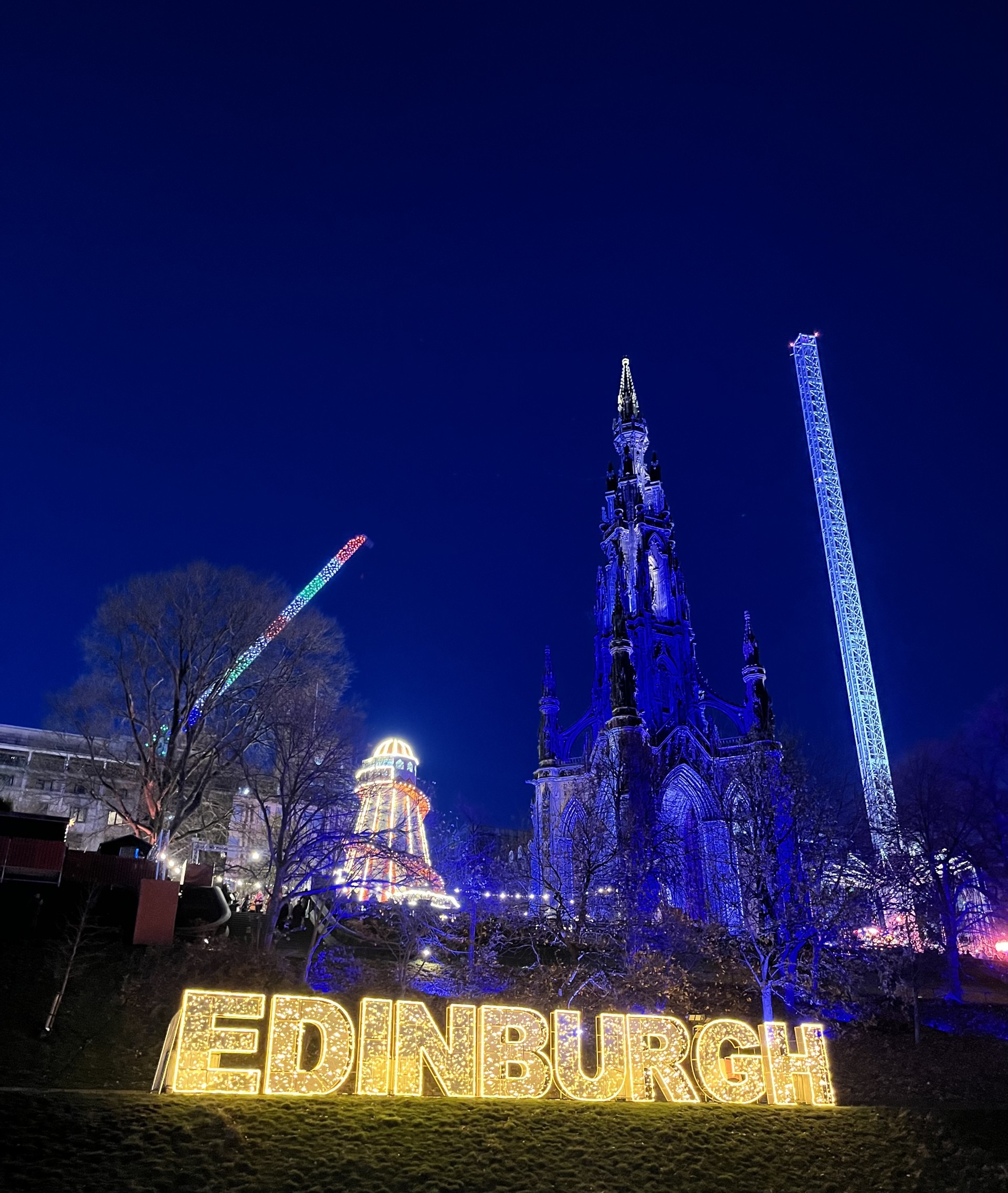 Edinburgh light-up sign and the Scott Monument in the Princes Street Festive Market at night