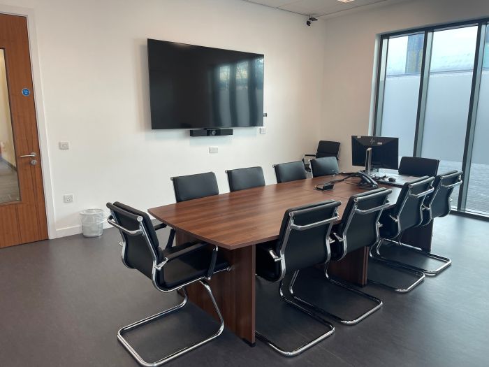 Flat floored meeting room with boardroom table and chairs, video monitor, and PC.