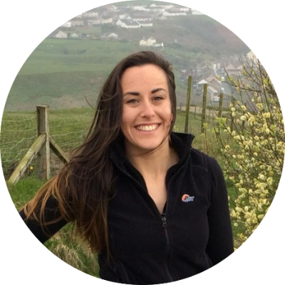 Headshot of Nina Gammage standing outdoors against a countryside background