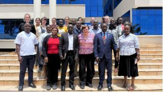 A group of people standing on steps in front of a building with blue-tinted windows