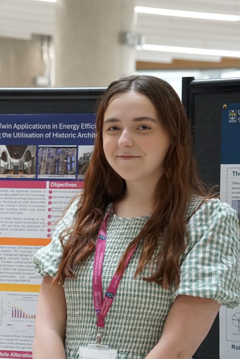 A student smiling in front of a research poster
