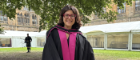 Dr Oweis standing in the east quad smiling in graduation robes