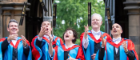Members of the band Deacon Blue in graduation robes throwing honourary diplomas up in the air