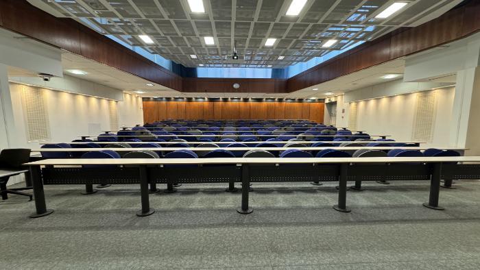 Raked lecture theatre with fixed seating and projector.