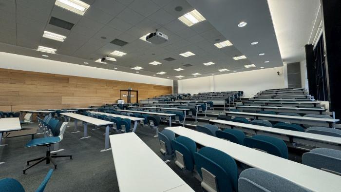 Raked lecture theatre with fixed seating, and projectors.