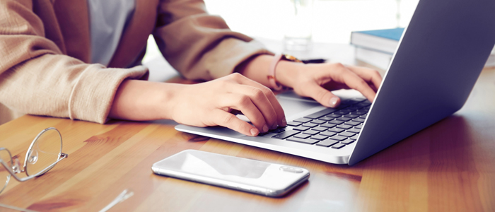 Photo of person on laptop with glasses and mobile