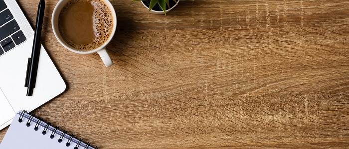 Photo of a wooden table with coffee, a notepad and pen