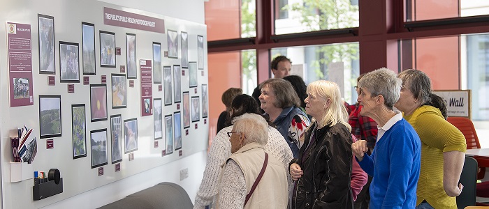 An image of people viewing the Byres Community Hub Photovoice at the launch